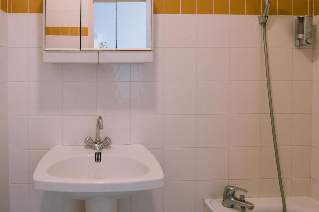 A bathroom with a white sink, a mirror, and a shower.