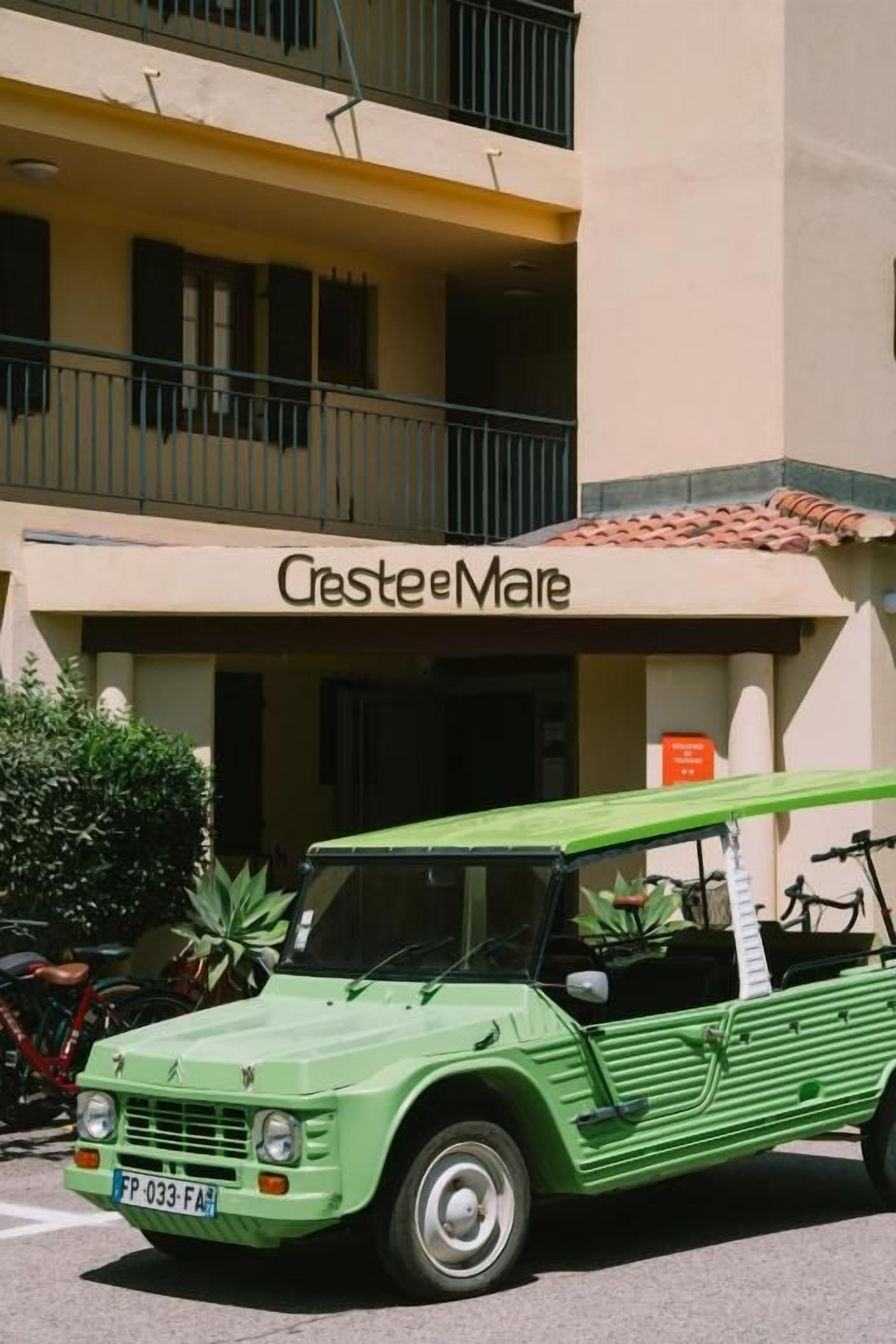 Un coche verde antiguo estacionado frente a un edificio con un letrero que dice 'Crestee Mare'.