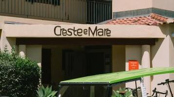 Un coche verde antiguo estacionado frente a un edificio con un letrero que dice 'Crestee Mare'.