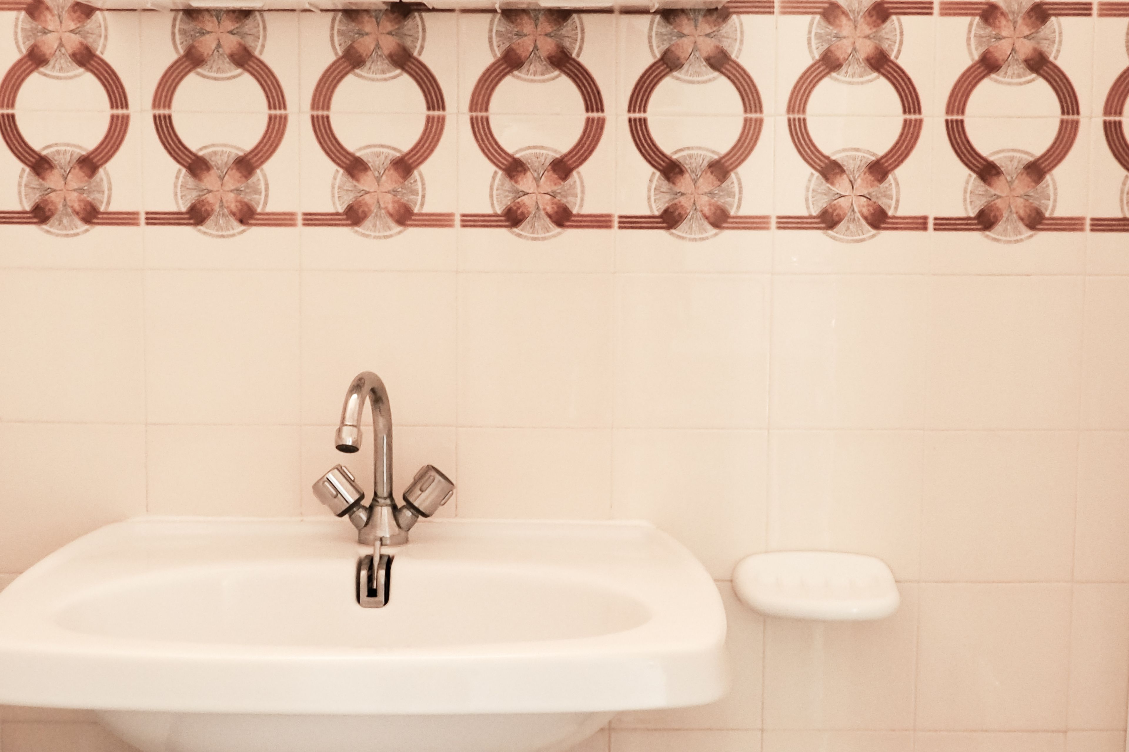Une salle de bain avec un lavabo blanc, un robinet et un porte-savon.
