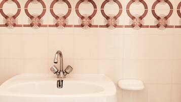 Une salle de bain avec un lavabo blanc, un robinet et un porte-savon.