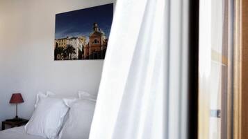 A hotel room with a bed, a nightstand with a lamp, and a framed picture on the wall.