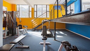 Een sportschool met fitnessapparatuur, een bank en een trap.