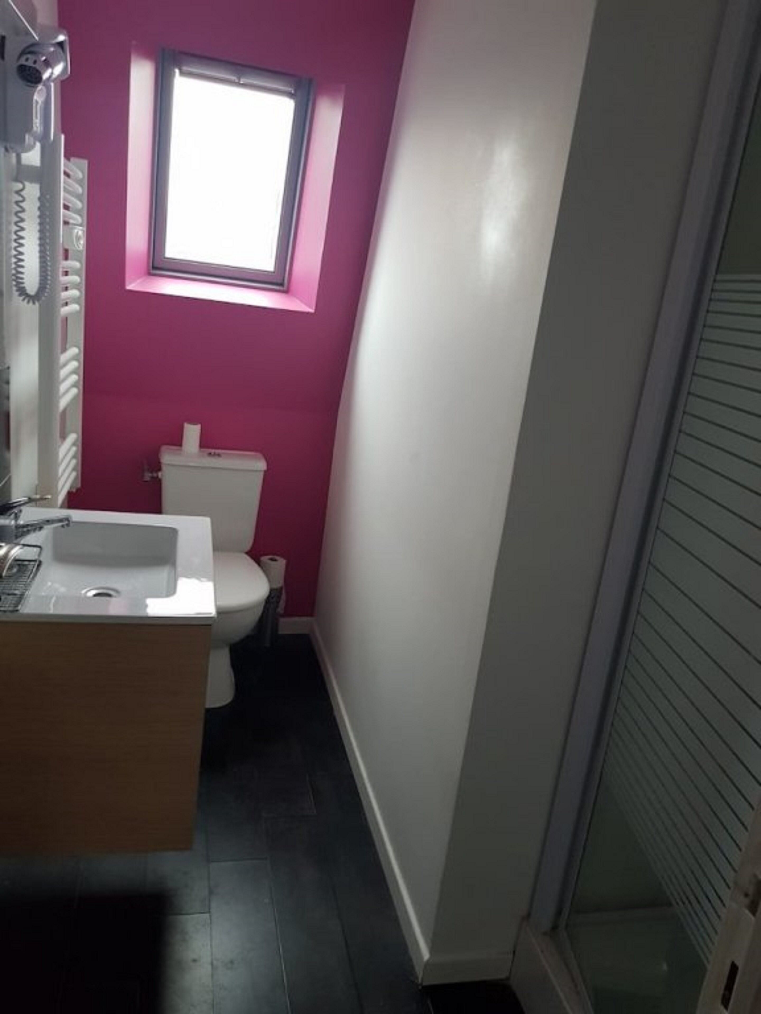 A bathroom with a white sink, toilet, and a window above the toilet.