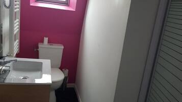 A bathroom with a white sink, toilet, and a window above the toilet.