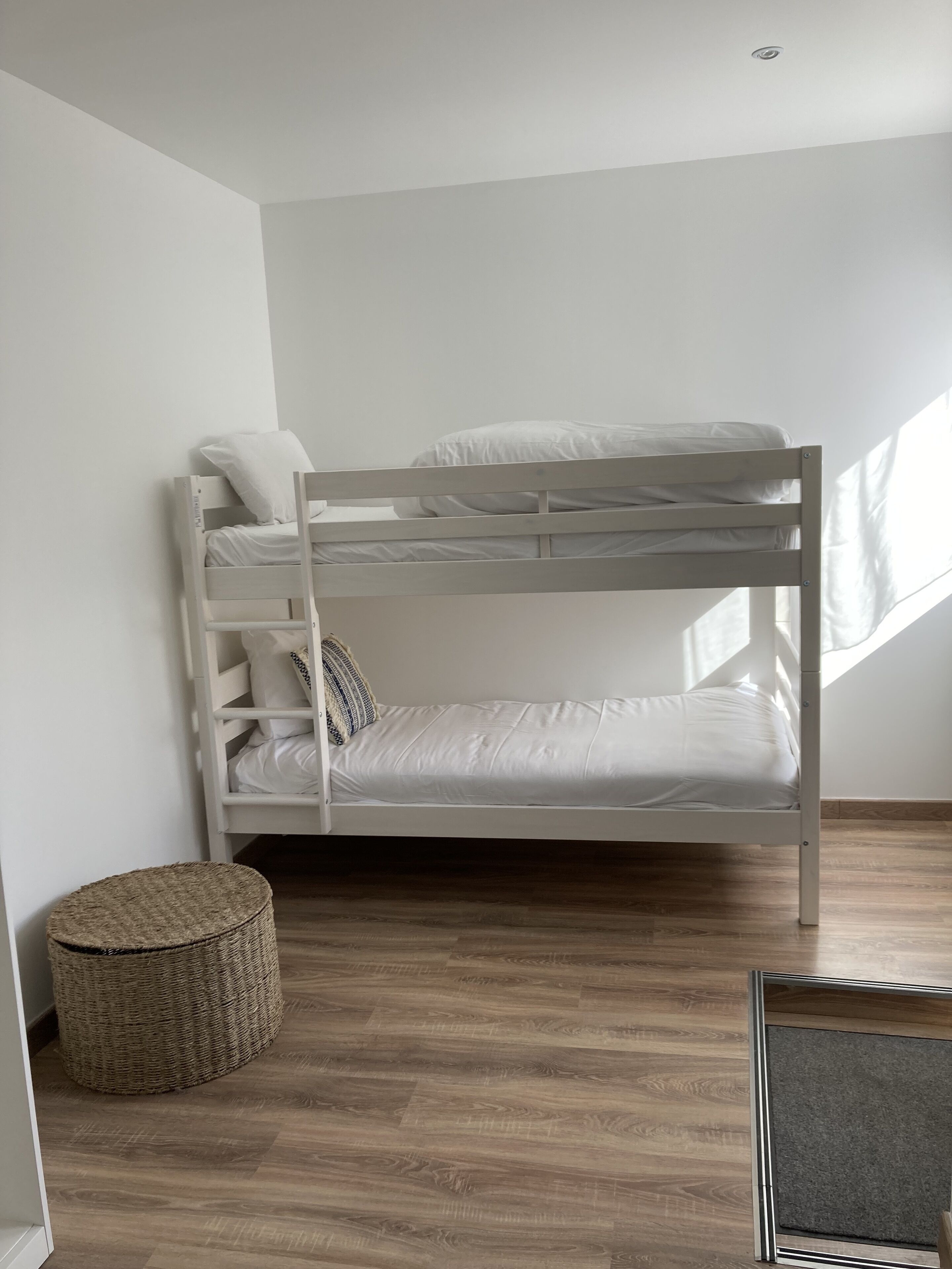 A bunk bed in a room with a wooden floor and white walls.