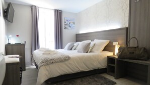 A neatly arranged bedroom with a bed, bedside tables, a nightstand, a lamp, and a handbag on the nightstand. - Hôtel Le St Patrice (Bayeux)