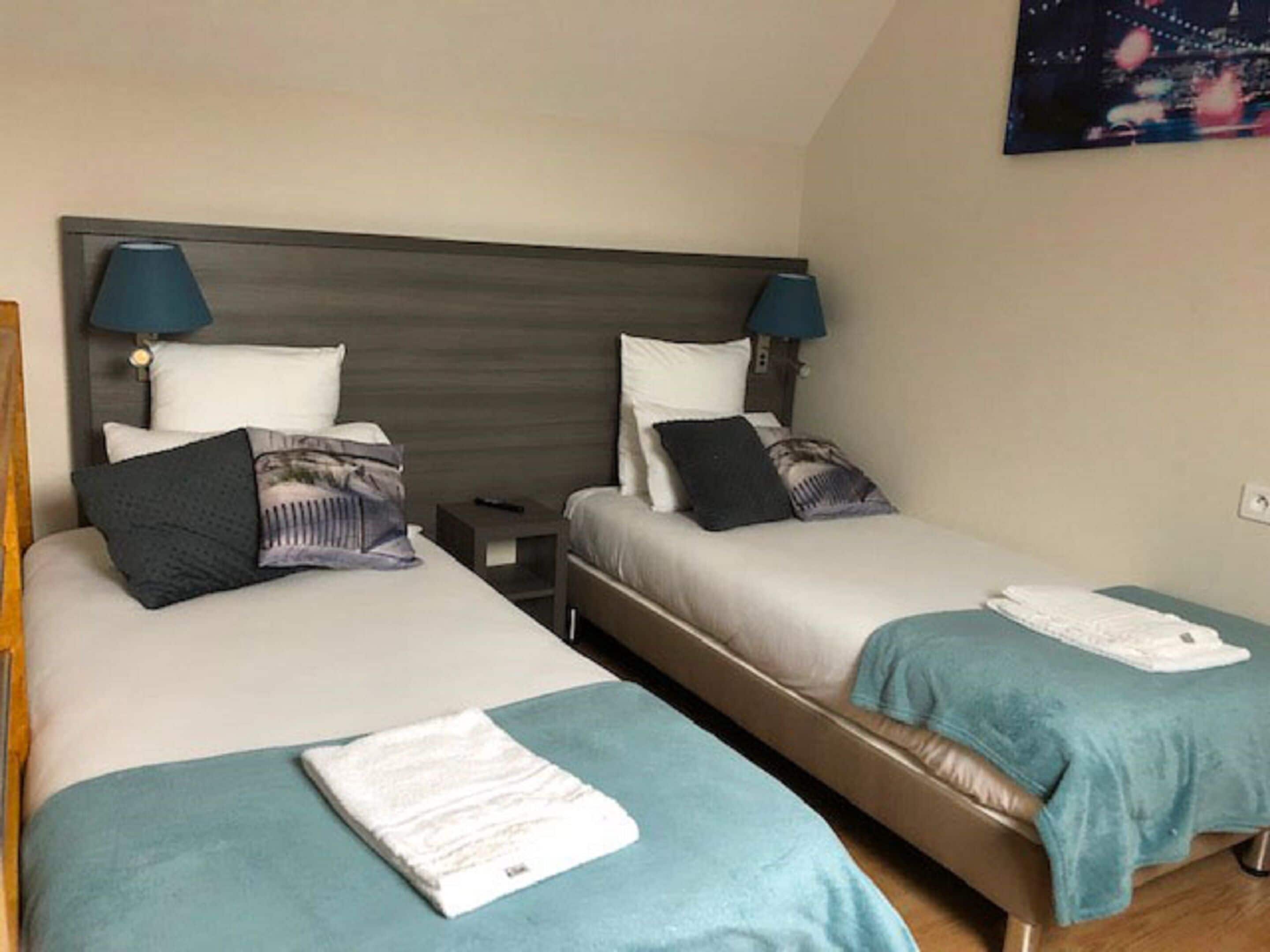 A hotel room with two beds, each with a pillow, a nightstand, and a lamp.