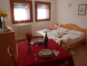 A neatly arranged bedroom with a wooden bed, a bedside table with a lamp, and a window with curtains.