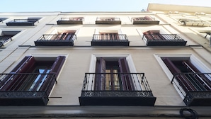 A building facade with multiple windows, some with shutters, and balconies with wrought iron railings. - Slow Suites Bellas Artes (Madrid)