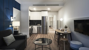 A modern living room with a sofa, a coffee table, and a dining area with stools. - Slow Suites Bellas Artes (Madrid)