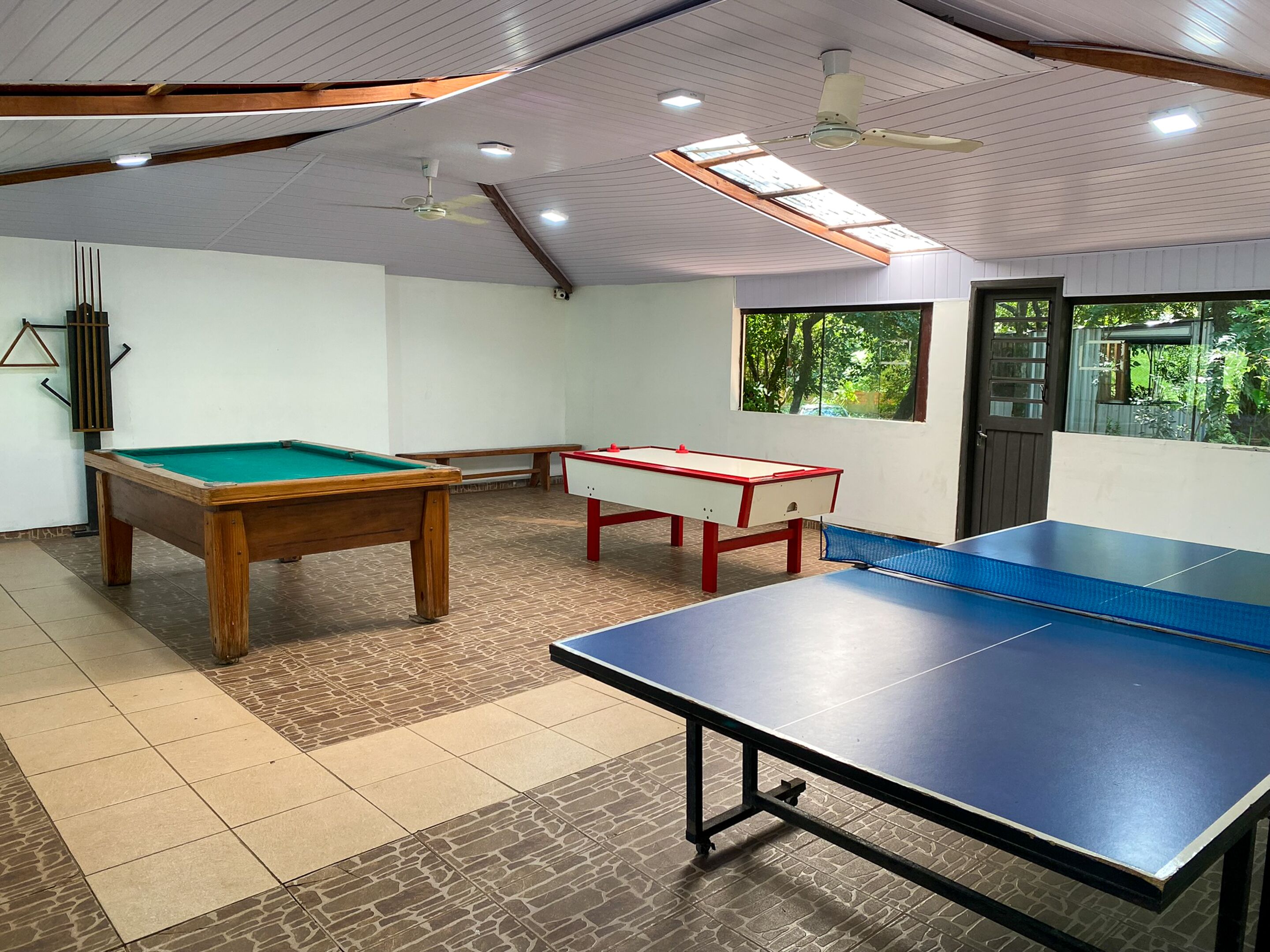 Una habitación con mesa de billar, mesa de ping pong y mesa de futbolín.