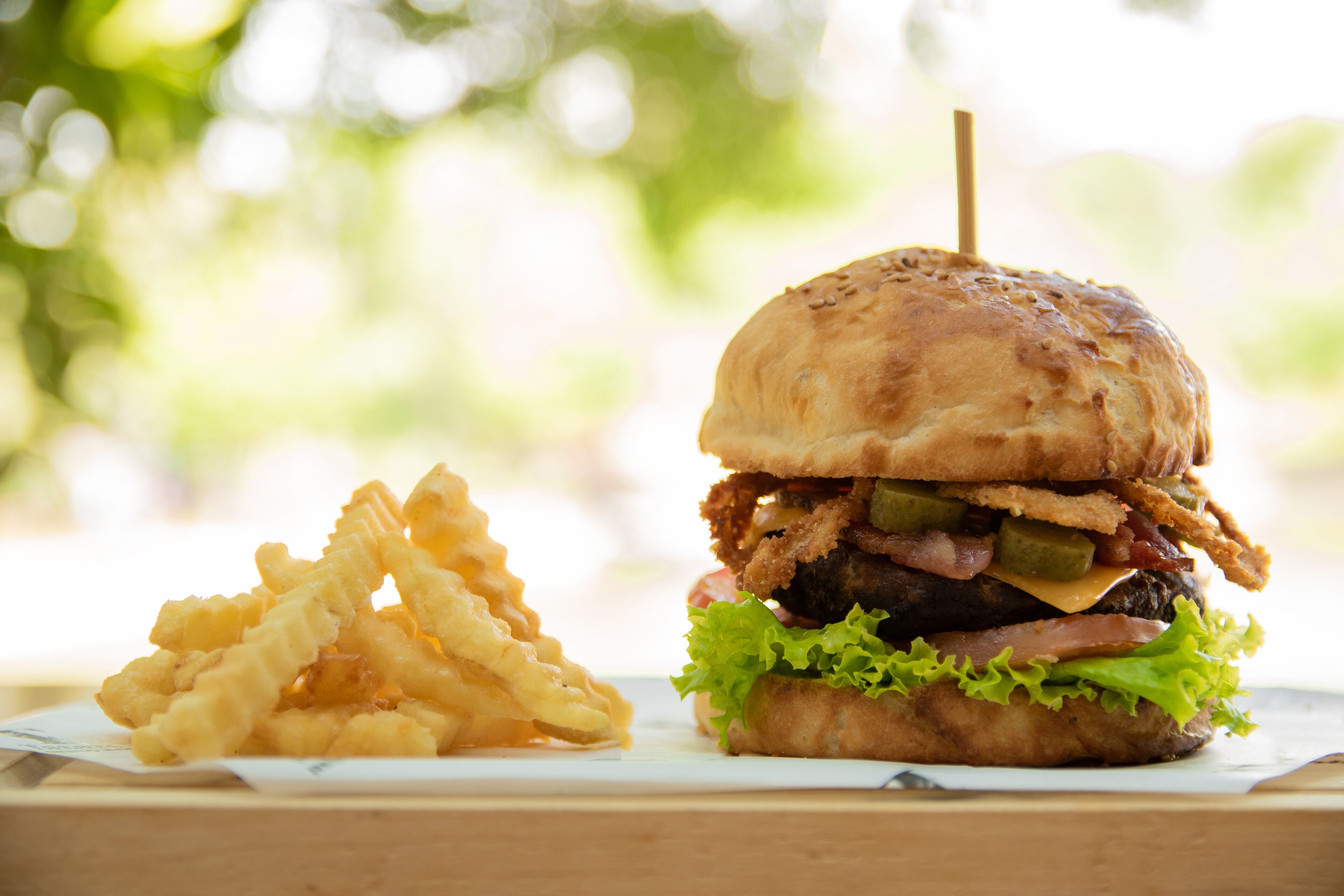 Un hamburger avec un pain, de la laitue et une portion de frites, le tout posé sur une surface en bois.