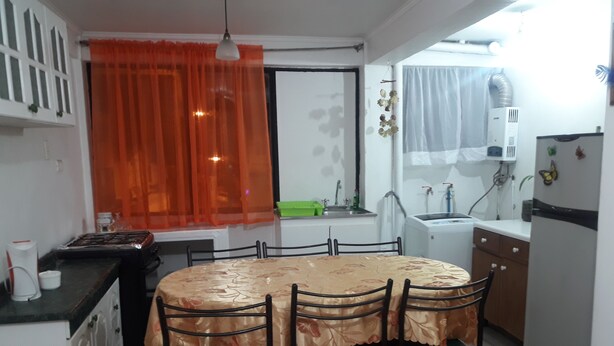 A compact kitchen with a dining table, chairs, and a refrigerator. - Depto Pedro Prado en Iquique 1119 (Iquique)