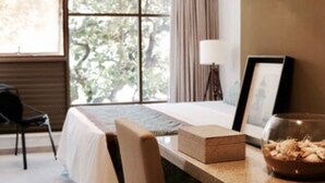 A hotel room with a bed, a dining table with chairs, a window with curtains, a lamp, and a framed picture on the wall. - Hotel do Mar Cabo Branco (João Pessoa)