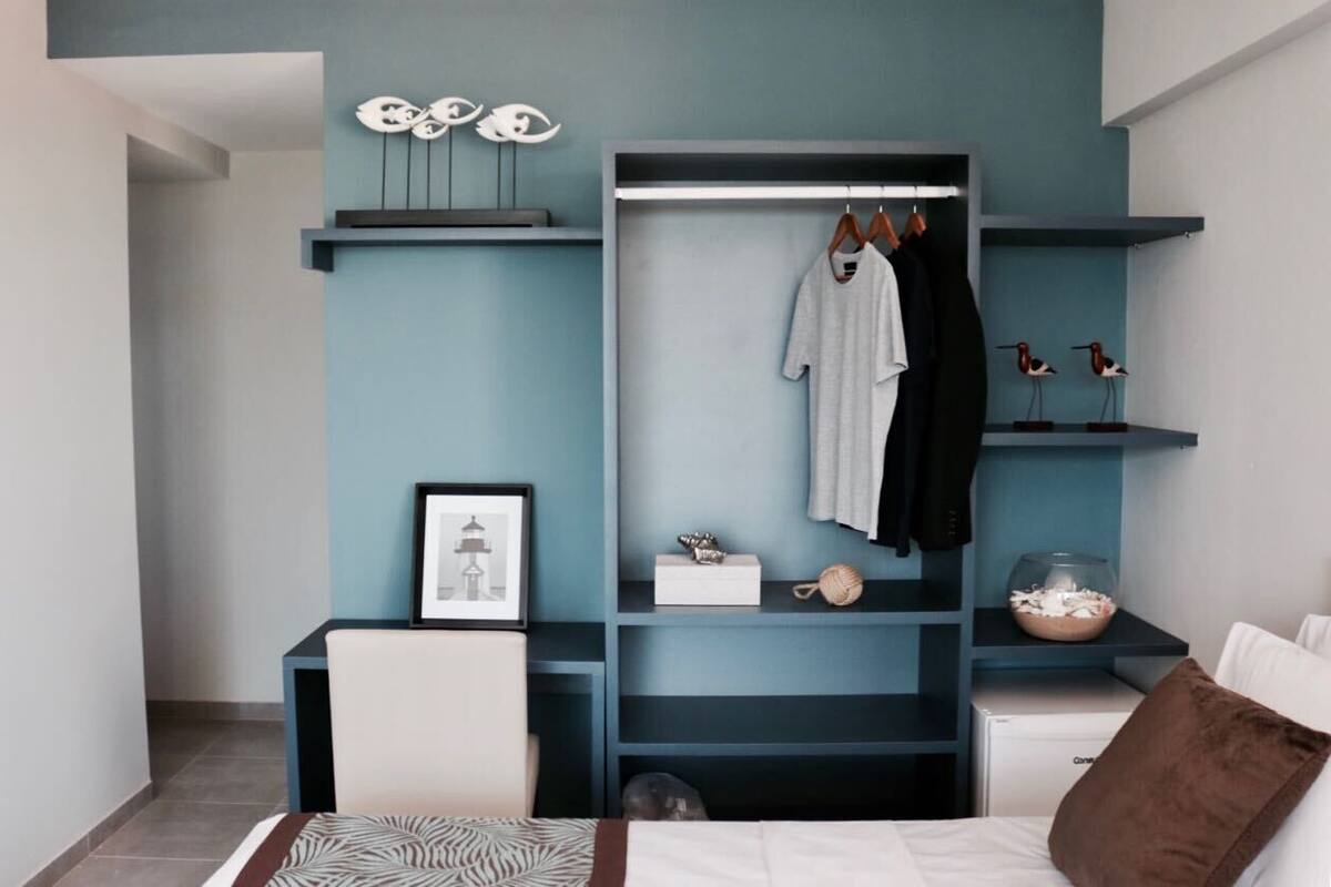 Une chambre à coucher comprenant un lit, un bureau, une chaise, une armoire et des étagères ornées d’objets décoratifs.