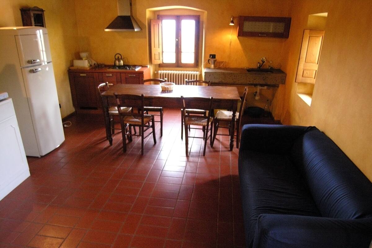 Une cuisine compacte comprenant une table à manger, des chaises, un réfrigérateur et un canapé.