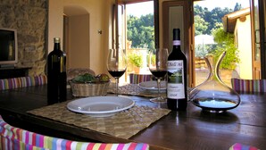 A dining table with plates, wine glasses, and a bottle of wine. - Agriturismo Il Bellini (Castelfranco Piandisco)