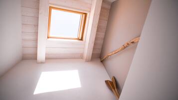 Una habitación con techo inclinado, tragaluz y viga de madera.