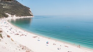 Una playa con agua turquesa cristalina, arena blanca y algunas personas.