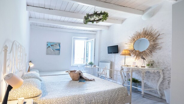 Un dormitorio con cama, mesita de noche, lámpara y un espejo decorativo.