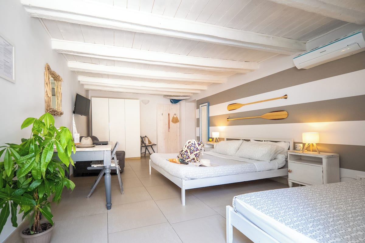 Een moderne slaapkamer met een bed, nachtkastje, lamp en een potplant.