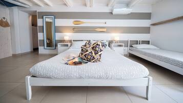 A modern bedroom with a large bed, two bedside tables, a mirror, and a ceiling fan.