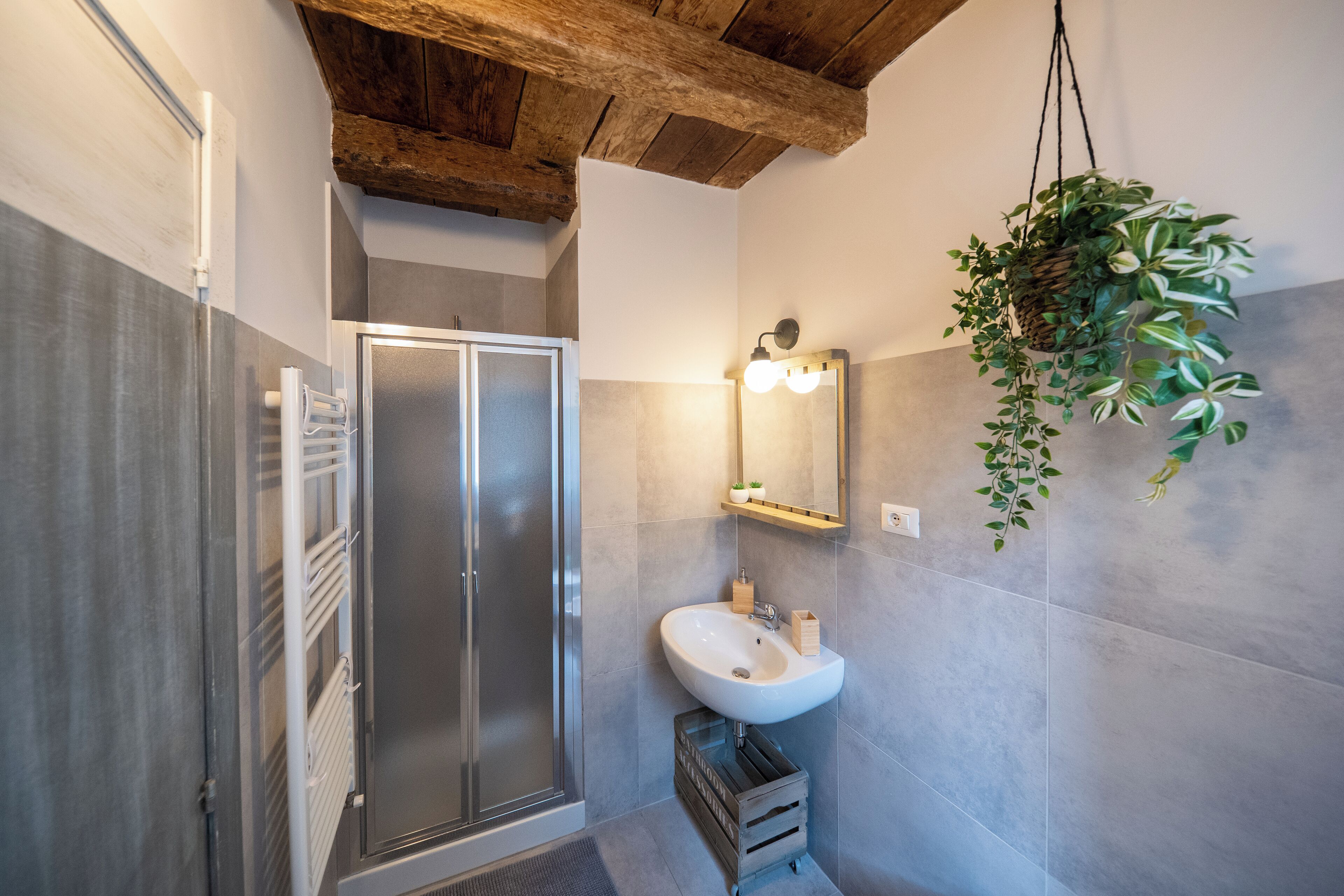 A modern bathroom with a glass shower, a white sink, and a wooden crate.