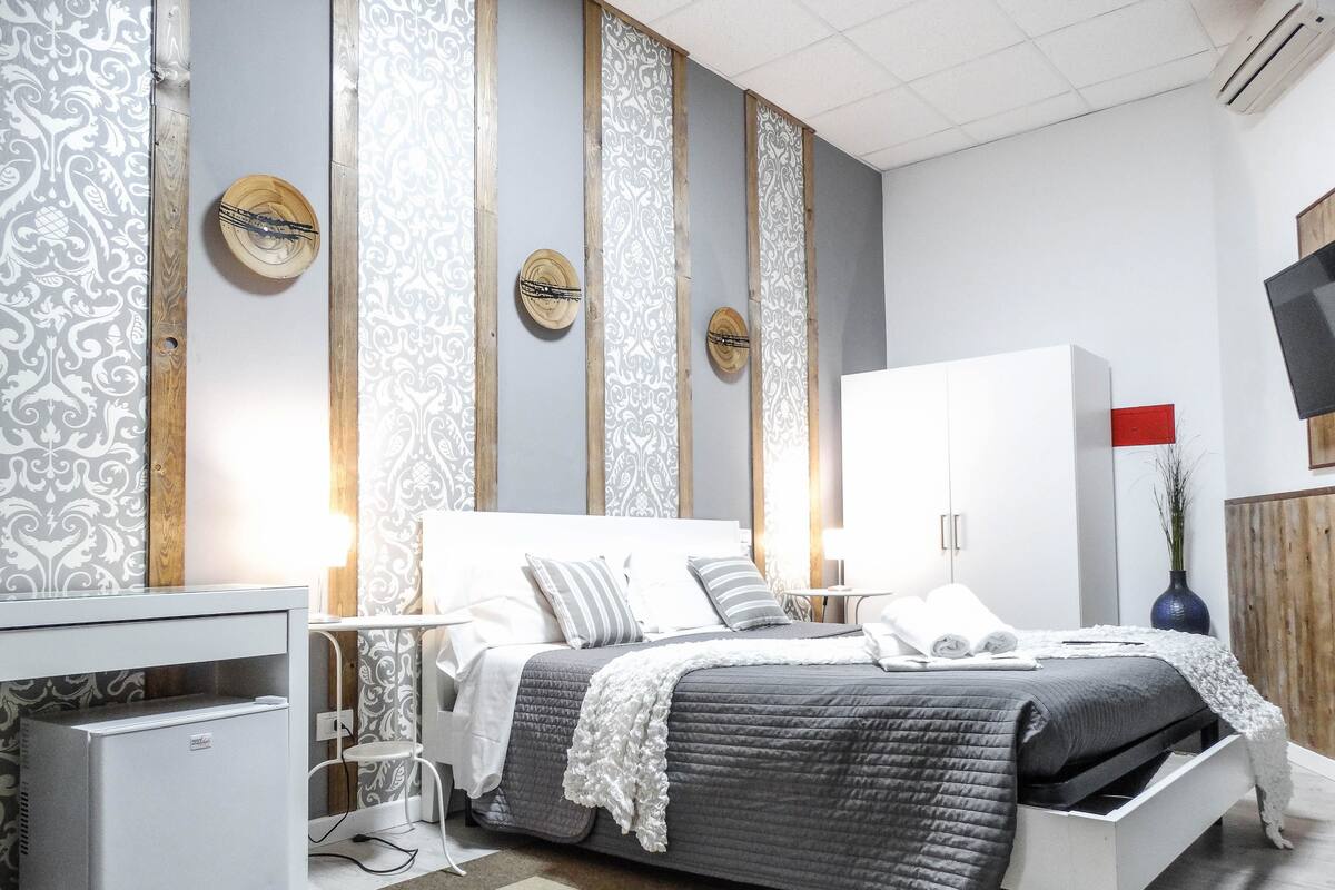 Un dormitorio moderno con cama, mesitas de noche, un armario y paneles decorativos en la pared.