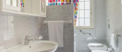 A bathroom with a white sink, a toilet, and a shower area.