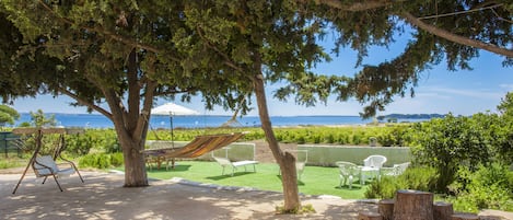 Un patio con mobiliario exterior, una hamaca y vistas al mar.