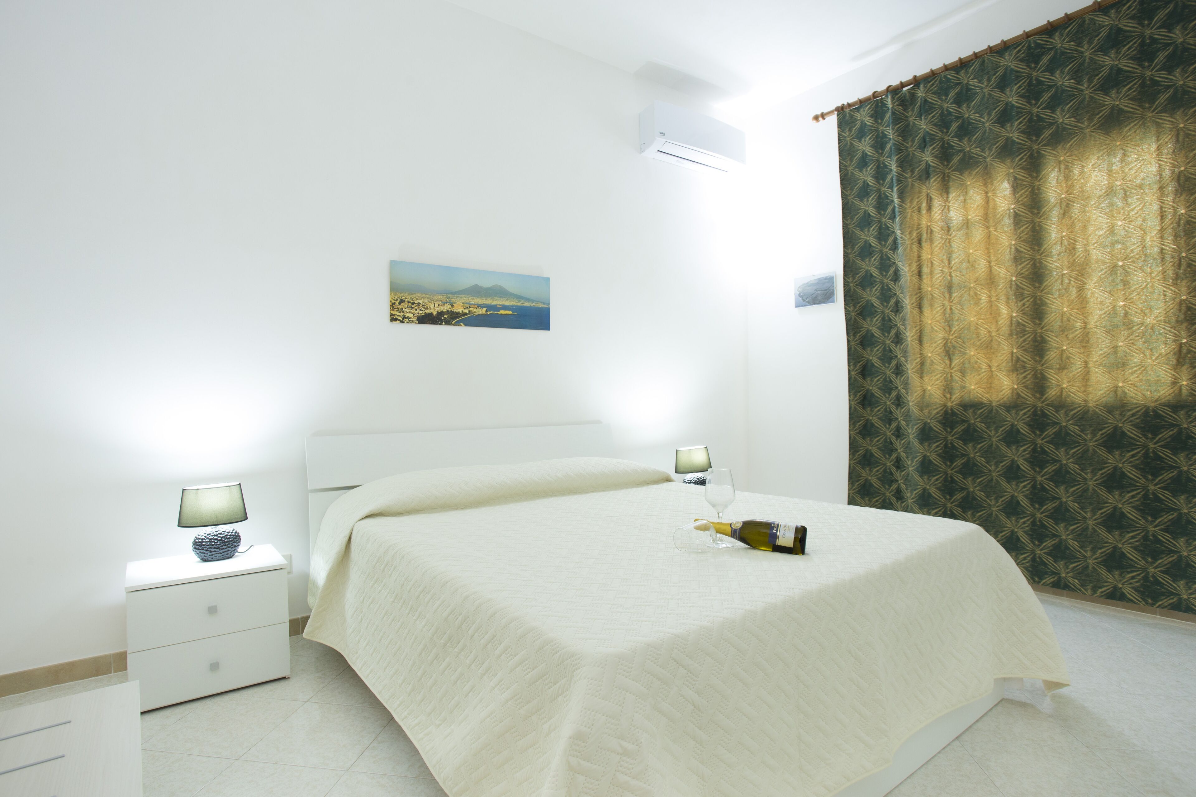 A neatly made bed with a white bedspread, a bedside table with a lamp, and a picture on the wall.
