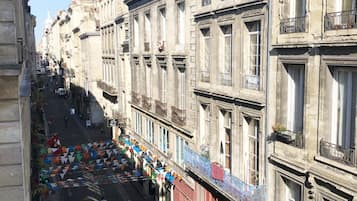 Straatbeeld met gebouwen in klassieke architectuur, een gele bestelwagen geparkeerd op de straat, en kleurrijke driehoekige vlaggen langs het trottoir.