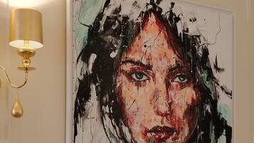Pintura numa parede, com um candeeiro de parede dourado à esquerda.
