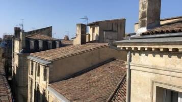 Una calle estrecha con edificios antiguos, una chimenea a la vista y un cielo azul despejado.