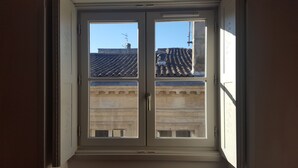 Ein Fenster mit Blick auf ein Gebäude mit einem Ziegeldach und einer Stein-Fassade.