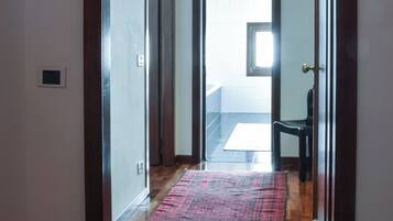 Un pasillo con piso de madera, un tapete rojo y una puerta que da a otra habitación.