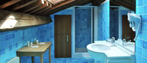 Un baño con azulejos azules, una mesa de madera, un lavamanos y una ducha.