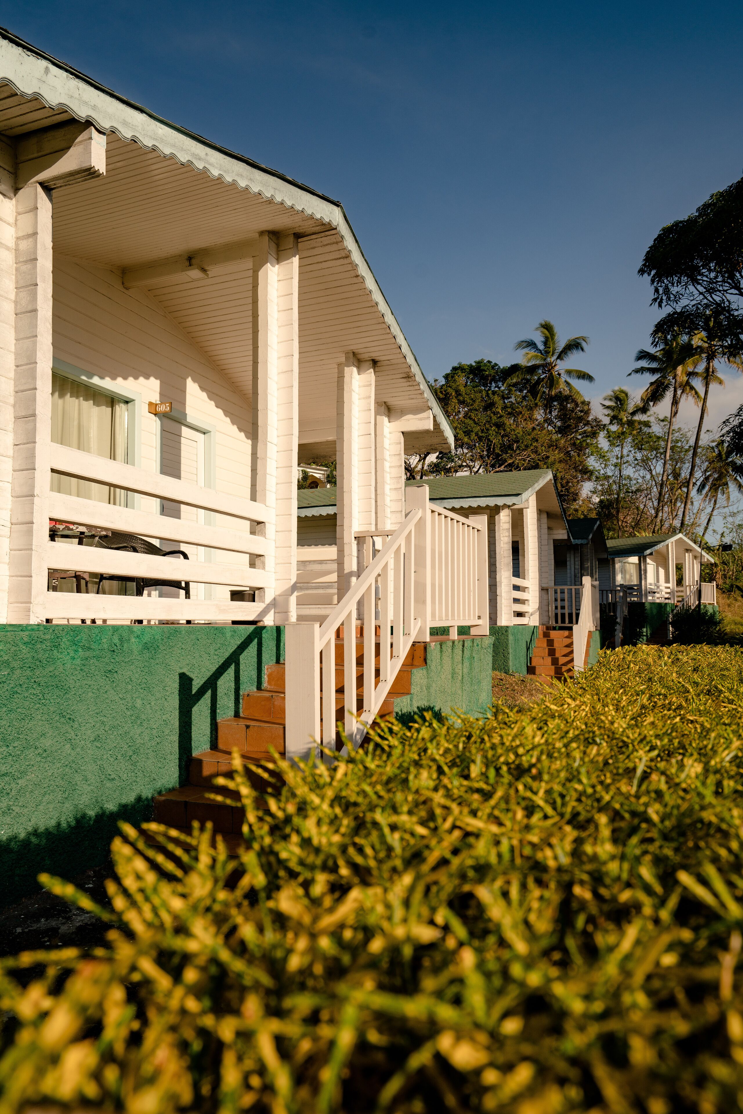 A row of white cabins with green awnings and wooden steps leading to the entrance.