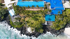 An aerial view of a resort with a blue-roofed building, a beach, and palm trees. -  Itsandra Beach Hotel & Resort (Batsa Itsandra)
