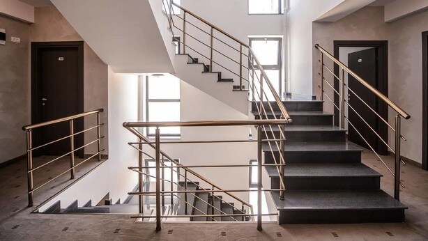 A modern staircase with metal railings, leading to a lower level.
