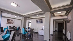 A modern dining area with a polished floor, grey and blue chairs, and a white tablecloth-covered table.