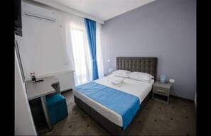 A hotel room with a bed, bedside table, and a small desk. - La mer Mamaia Nord (Navodari)