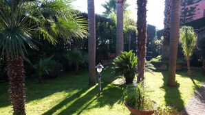 A garden with palm trees and a lamp post. - B&B Villa Hirschen (Zafferana Etnea)