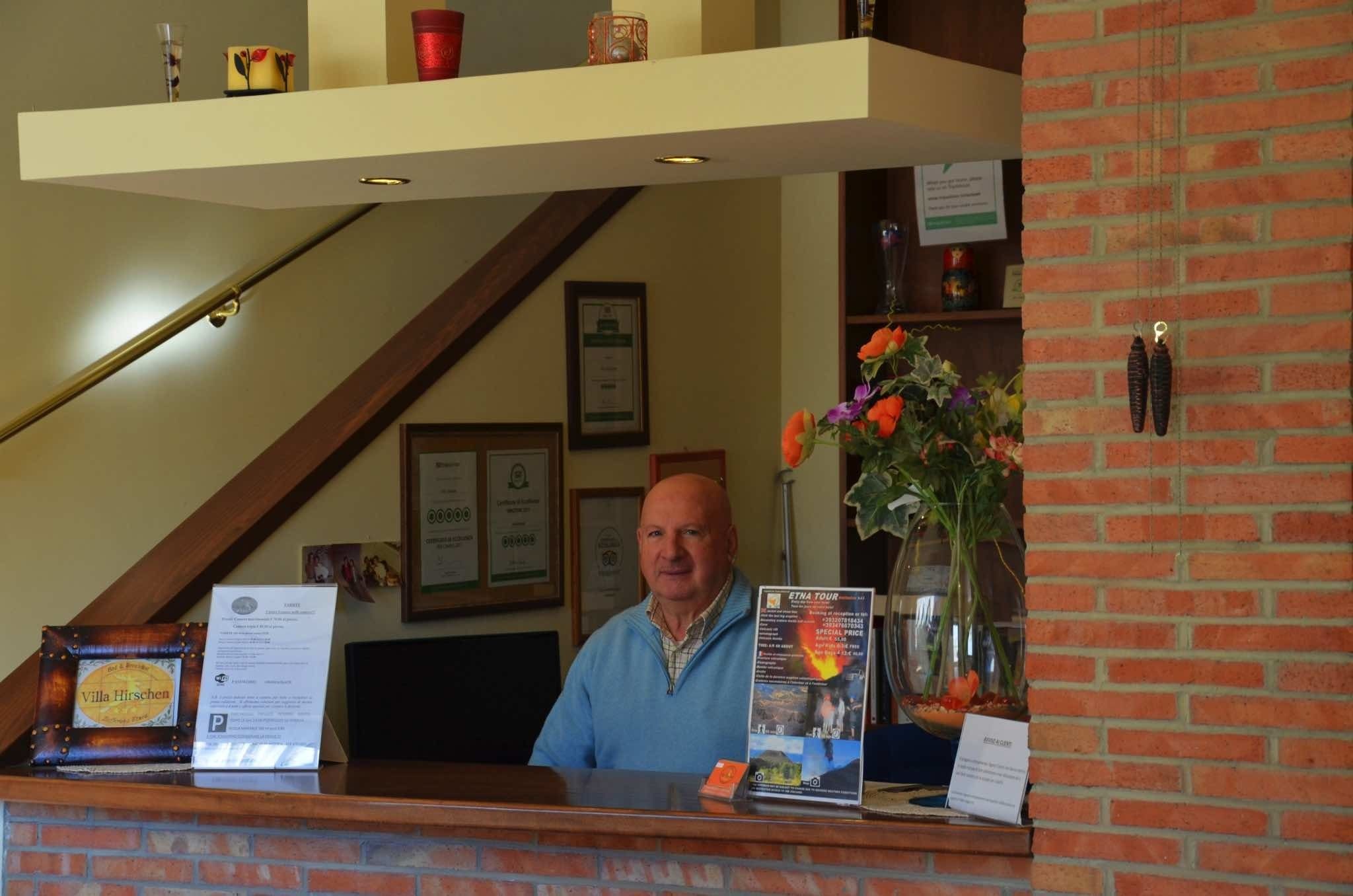 A reception desk with a framed certificate, a brochure, and a vase with flowers.