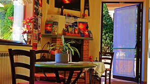 A dining area with a table, chairs, and a television on the wall. - B&B Villa Hirschen (Zafferana Etnea)
