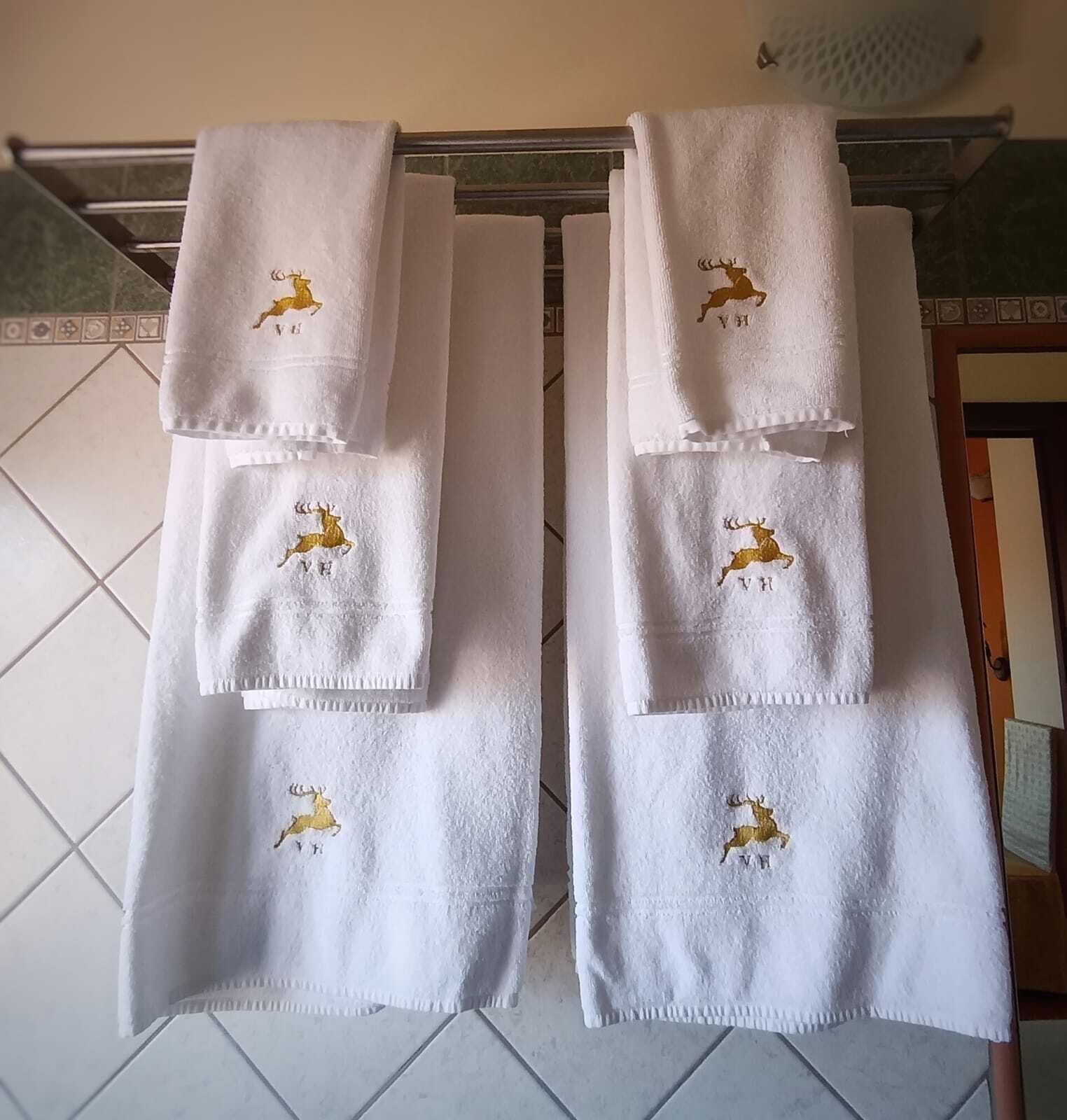 Two white towels with golden deer embroidery hanging on a rack.