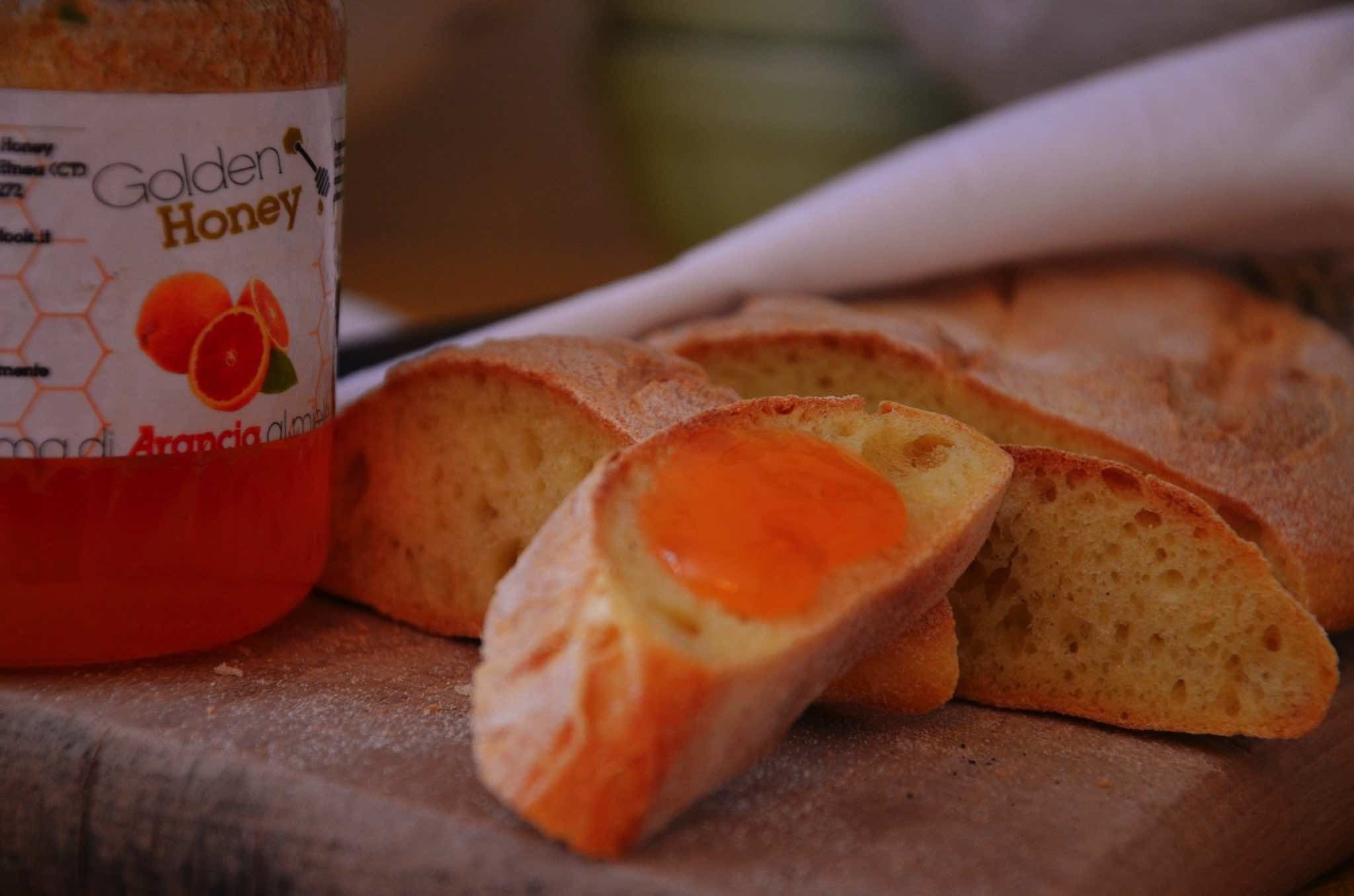 Ein Brot mit goldbrauner Honigschicht und eine Flasche mit dem Aufdruck "Golden Honey".