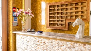 A hotel reception desk with a marble counter, a vase of flowers, a phone, and a keycard holder with room numbers. - Hotel Suiza Peruana (Huaraz)