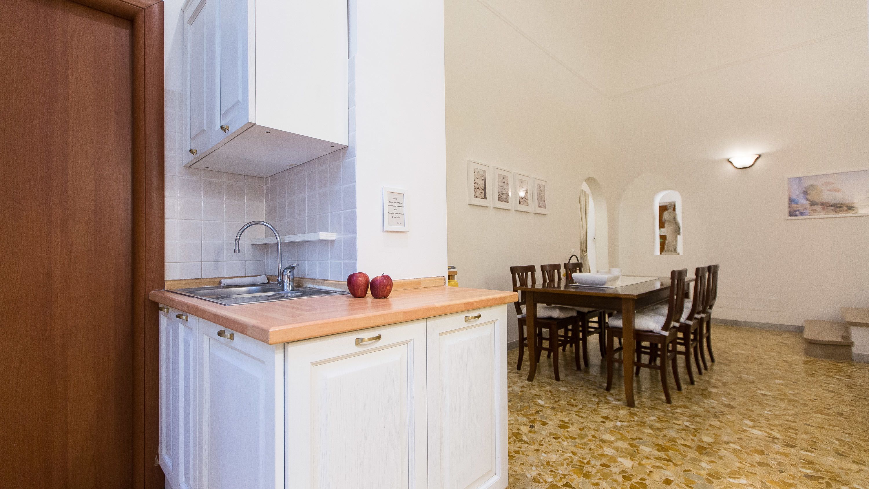 A compact kitchen with a sink, cabinets, and a dining area with chairs and a table.